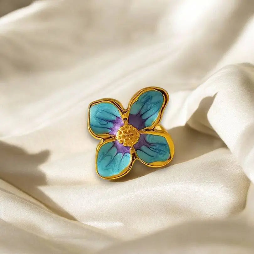 Eleganter Four Leaf Ring mit goldener Fassung und blauer Blütenverzierung. Perfektes Schmuckstück für stilvolle Akzente zu jedem Anlass.