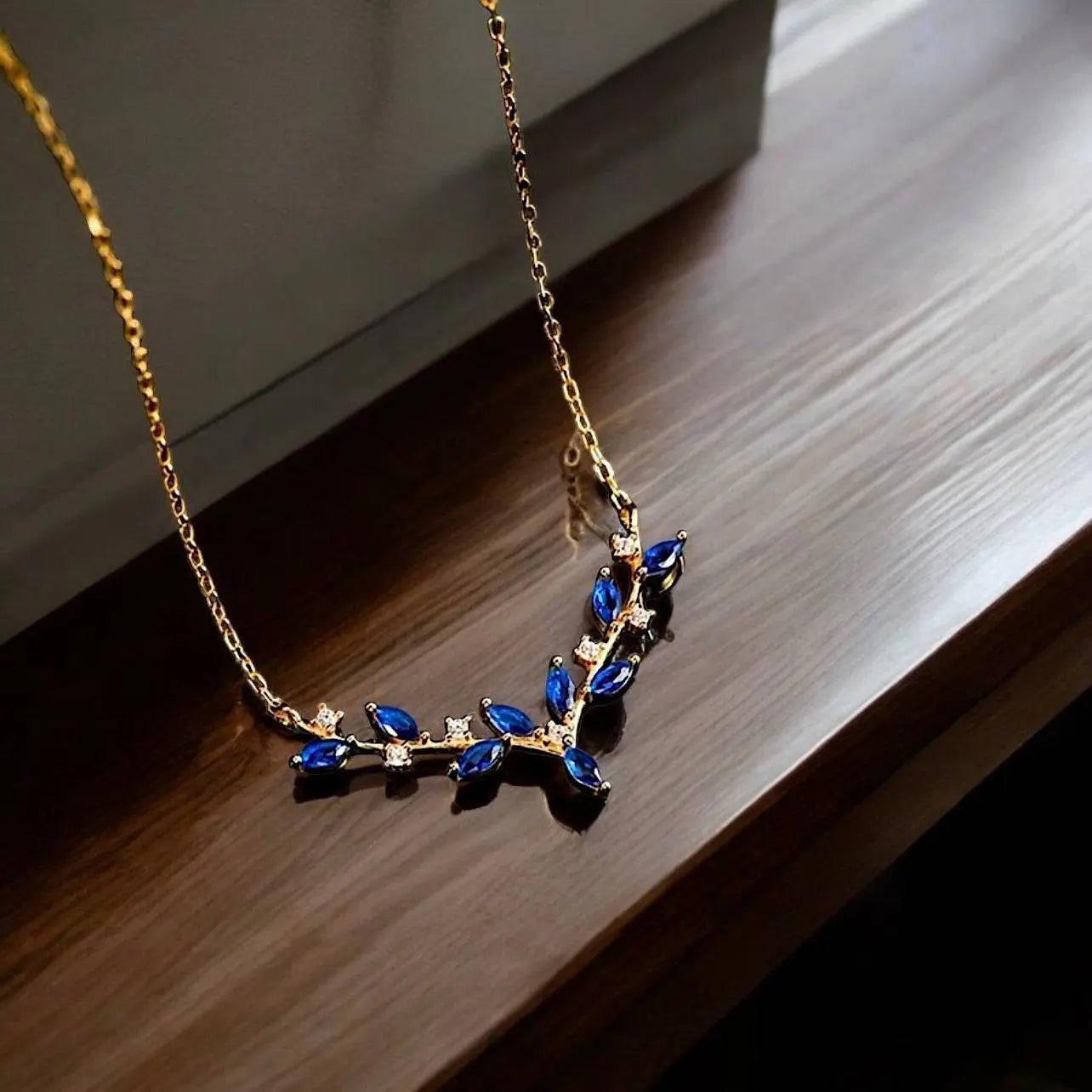 Elegante Halskette 'Deer Antler' mit goldener Kette und blauen Edelsteinen in Geweihform. Stilvolles Schmuckstück für besondere Anlässe.
