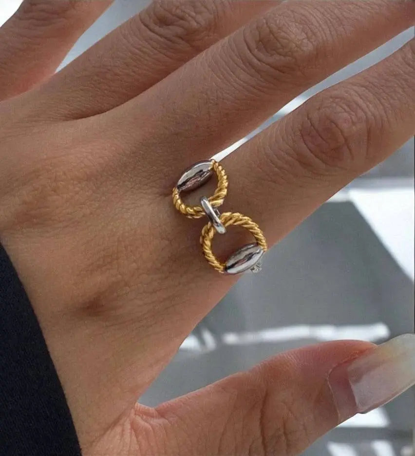 Eleganter Chunky-Ring mit goldenen und silbernen Details, verziert mit geflochtenem Design. Stilvolles Schmuckstück für moderne Looks.