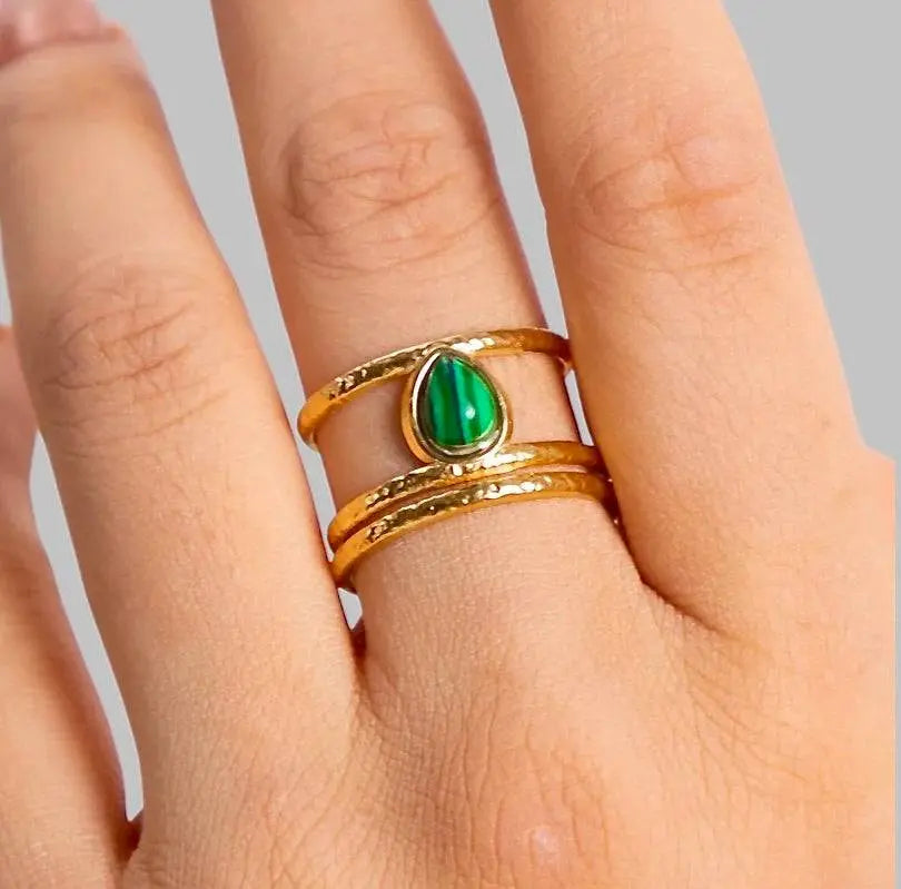 Eleganter goldener Ring mit tropfenförmigem Malachit-Stein, offenes Design und gehämmerte Textur. Stilvolles Schmuckstück für besondere Anlässe.
