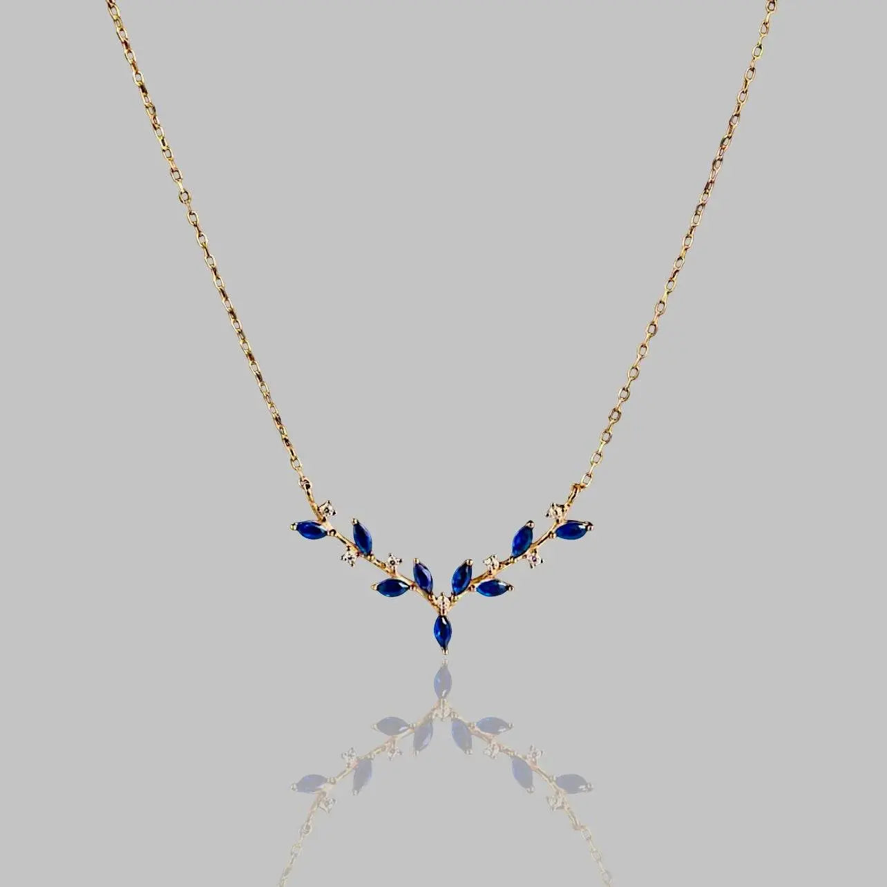 Elegante Halskette 'Deer Antler' mit goldener Kette und blauen Edelsteinen in Geweihform. Stilvolles Schmuckstück für besondere Anlässe.