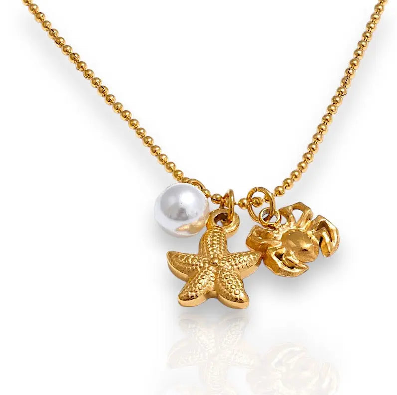 Halskette "Ocean Treasure" mit goldenen Anhängern in Form eines Sterns und einer Krabbe sowie einer Perle.