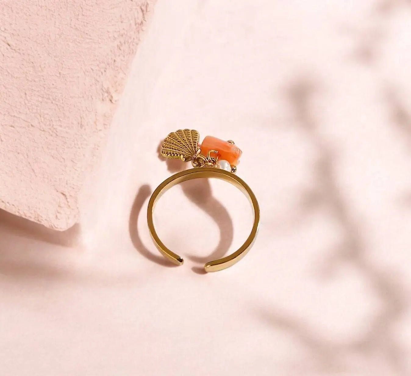 Eleganter goldener Ring Glossy Shell mit Muschel-Anhänger, Perle und Korallen-Detail. Perfektes Schmuckstück für stilvolle Looks.