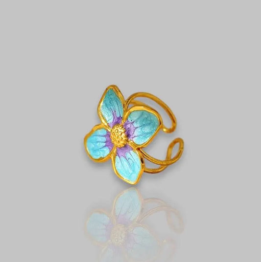 Eleganter Four Leaf Ring mit goldener Fassung und blauer Blütenverzierung. Perfektes Schmuckstück für stilvolle Akzente zu jedem Anlass.