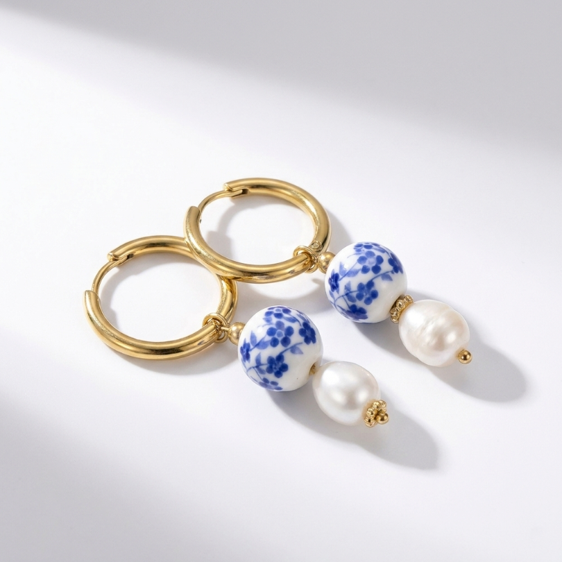 Blue Orchid Ohrringe aus 18KGP: goldene Creolen mit blau-weißen Porzellanperlen und weißen Perlenanhängern.