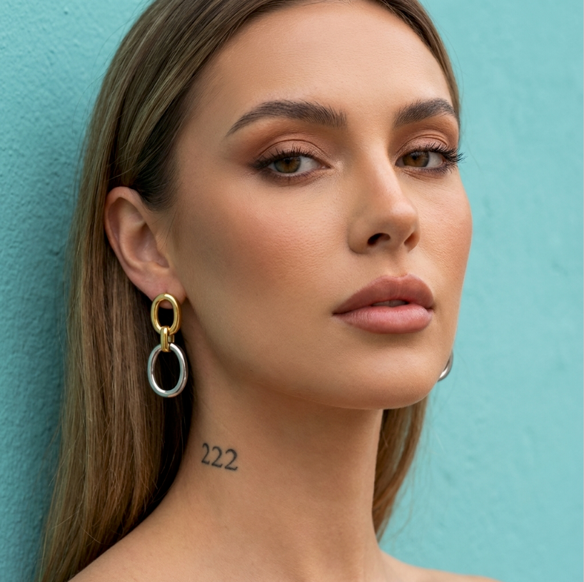 Silver & Sun Ohrringe: goldene und silberne Kreise an einer Frau vor türkisfarbenem Hintergrund.