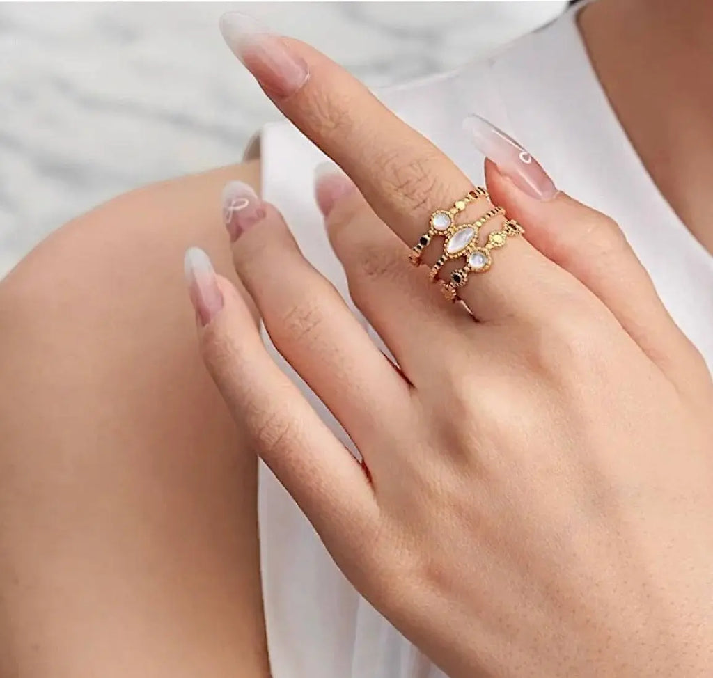 Eleganter goldener Ring Shelly mit filigranen Details und drei weißen Schmucksteinen. Stilvolles Accessoire für besondere Anlässe.